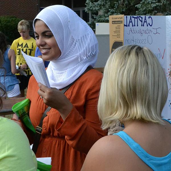 An international student provides information at a booth during Capital's welcome weekend